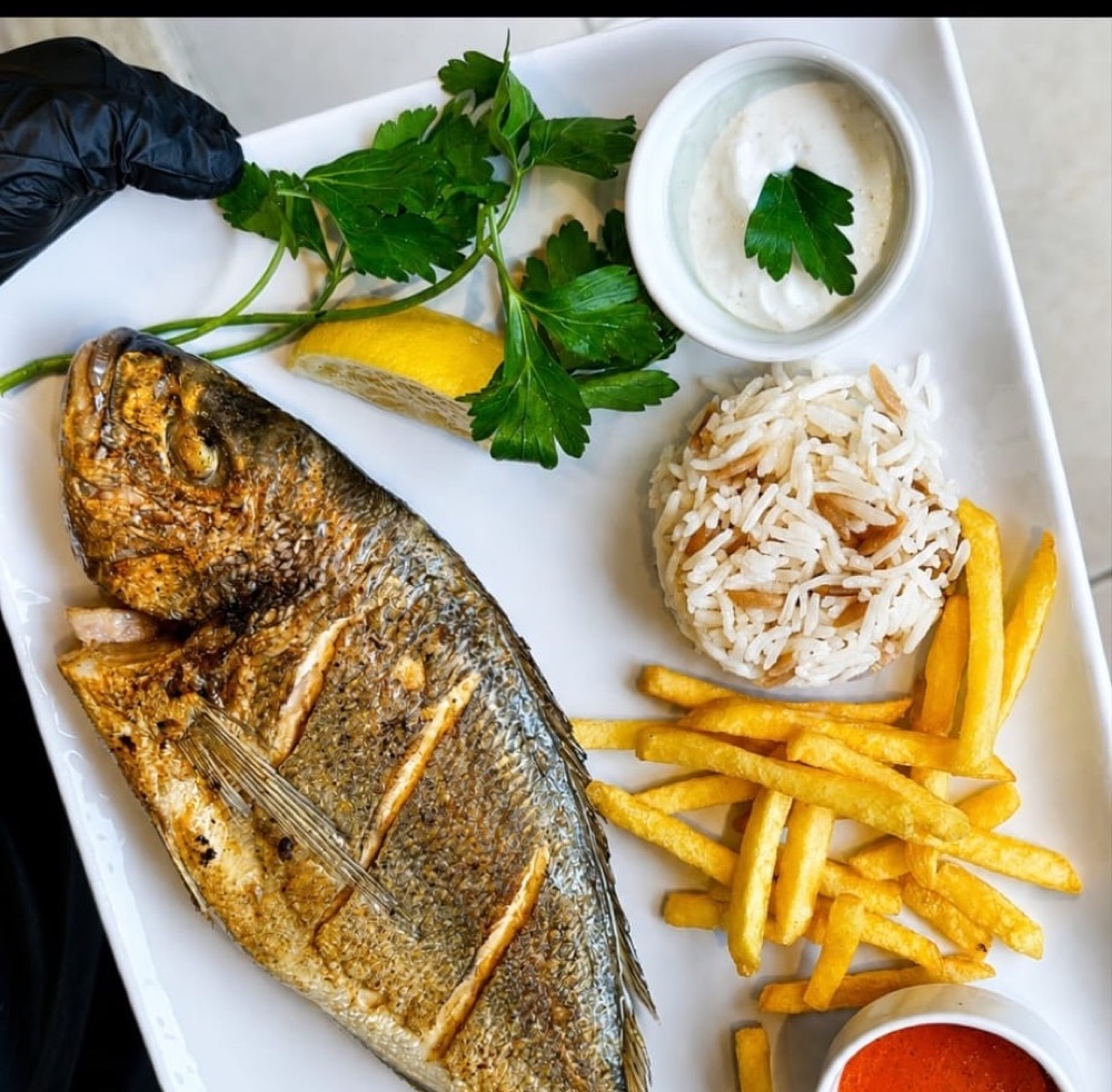 Etna Fish House Kaş'ta pilav ve patates kızartması eşliğinde bütün ızgara çipura